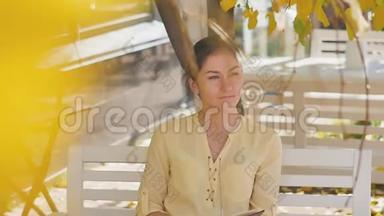 <strong>奇妙</strong>的秋景。 一位迷人的年轻女子坐在街头咖啡馆的桌子旁开心地笑着